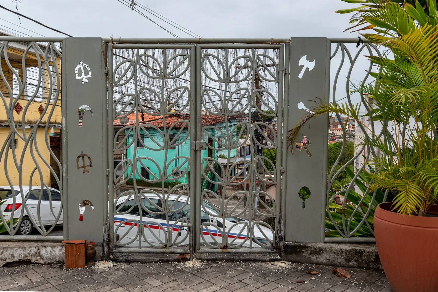 Área externa do gradil personalizado do Gantois (perfis em folhas e símbolos dos Orixás, cujo desenho foi criação da Iyá Kekeré Ângela Ferreira), delimitando o perímetro de tombamento do monumento histórico que resguarda o Memorial.